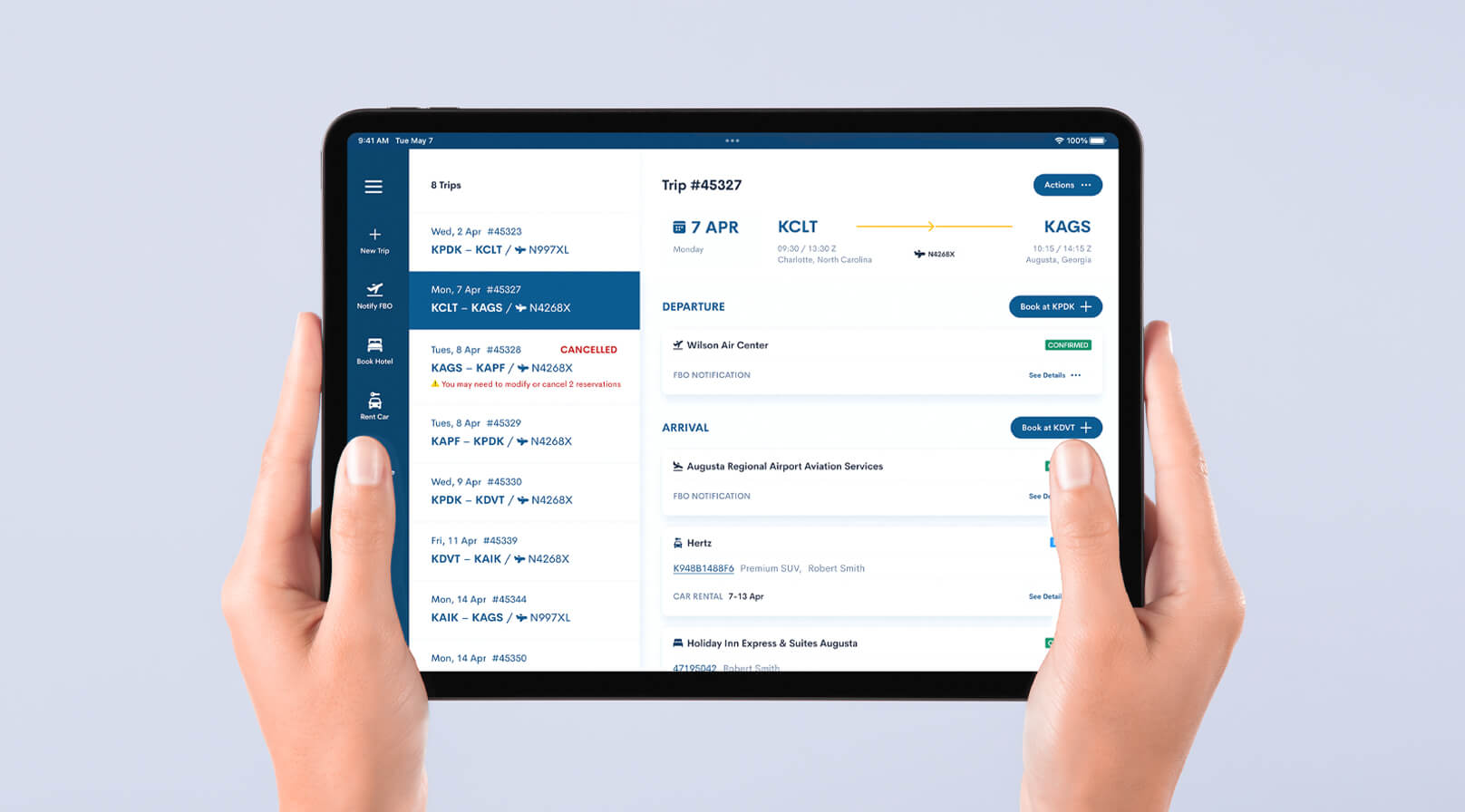 Two hands holding a tablet displaying the trip management app